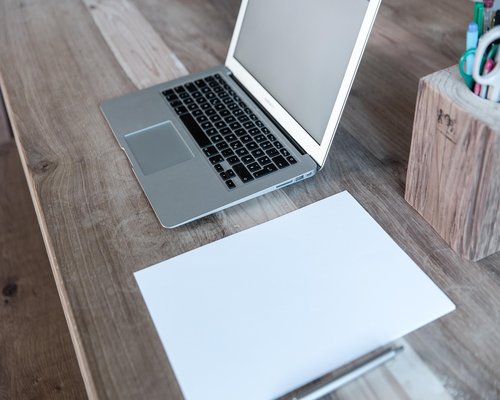 Minimalist wooden workspace desk setup containing a plain writing notebook and notebook accessories