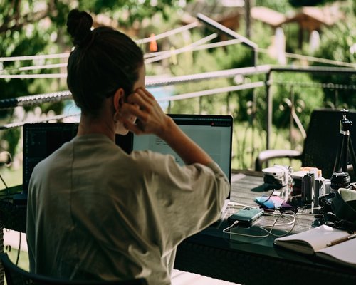 A relaxed professional taking a screen break by looking away from the desk toward a clean green outdoor landscape