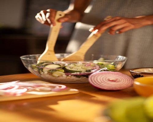 Person preparing a diverse fresh green salad mixed with dynamic Mexican ingredients inside a modern kitchen room